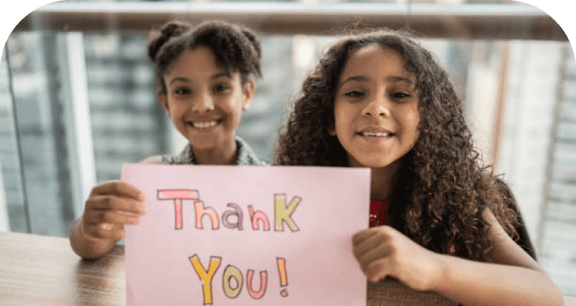 Two girls holding a handmade Thank You sign