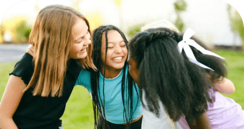 Four girls laughing and huddling together outdoors